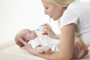 Mamma con il bambino e l'aspiratore nasale